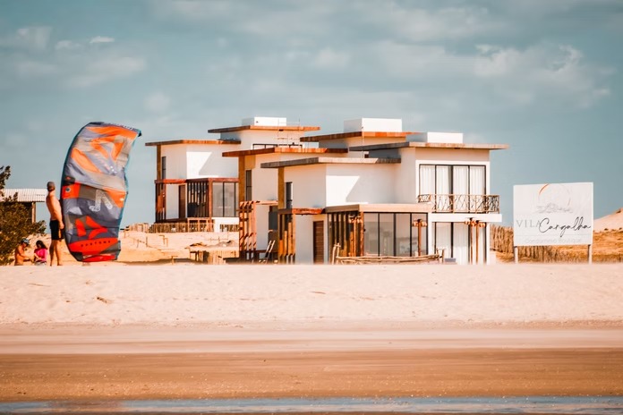 Vila Cangalha vista da praia de Caraúbas, com kitesurf no mar de Camocim, Ceará