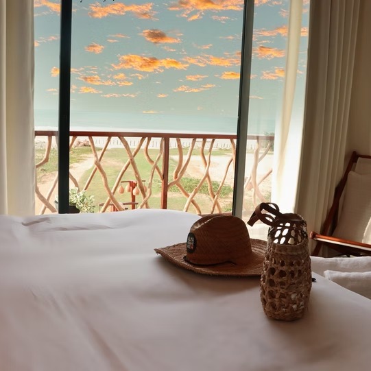 Suíte da Vila Cangalha com cama de frente para janela com vista do mar